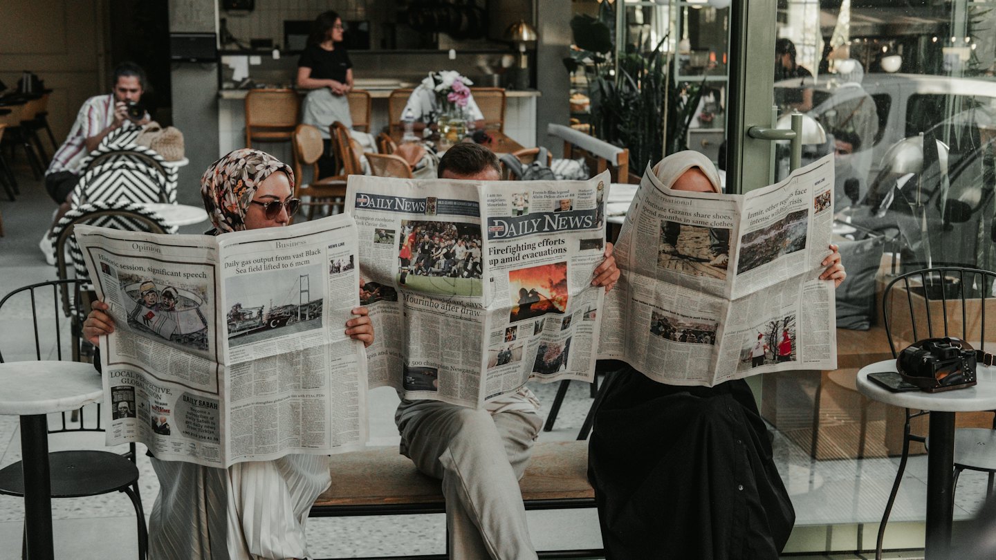 Persone che leggono il giornale in un bar all'aperto.